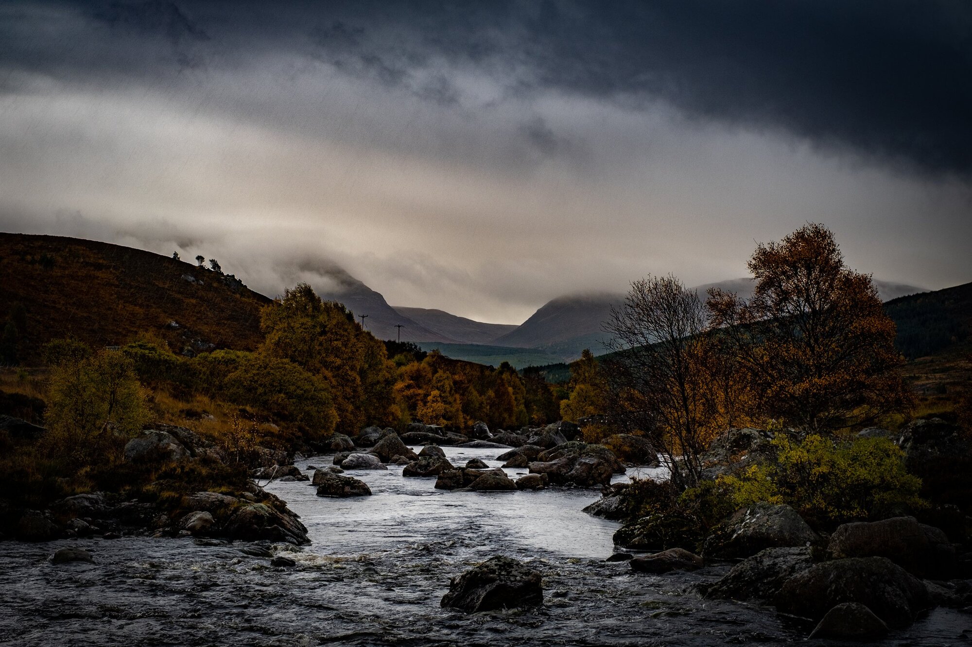 A river tumbling through autumn moorland under storm clouds