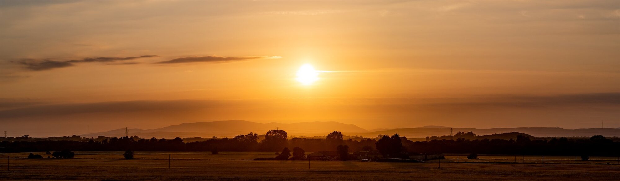 The sun setting in orange over a dark, flat horizon