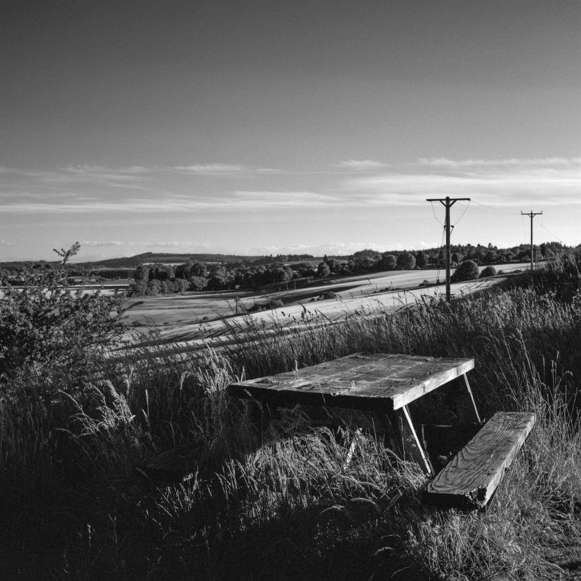 An old picnic table in long grass above the fields