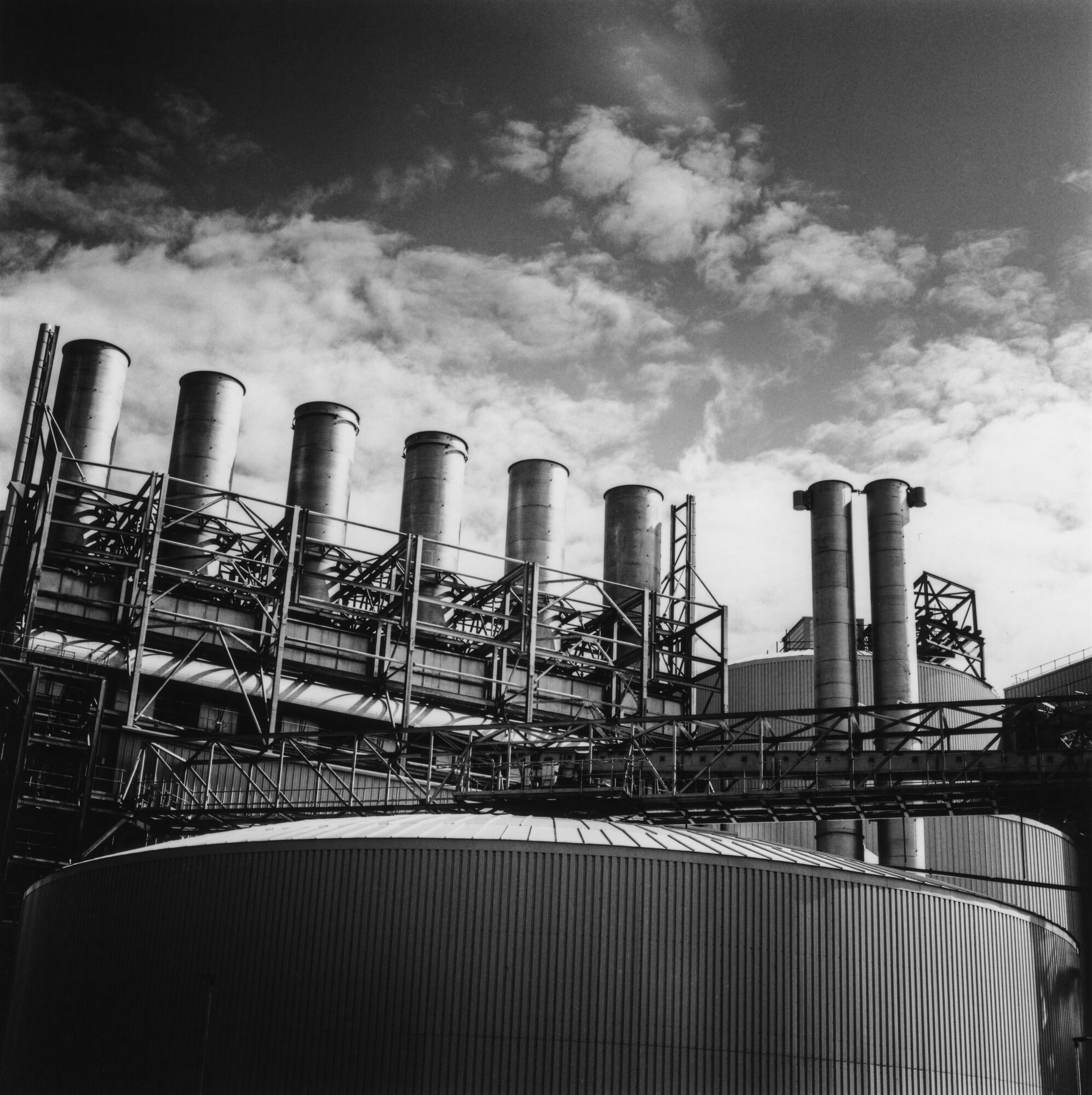 Chimney stacks and gantries of the maltings above a round tank