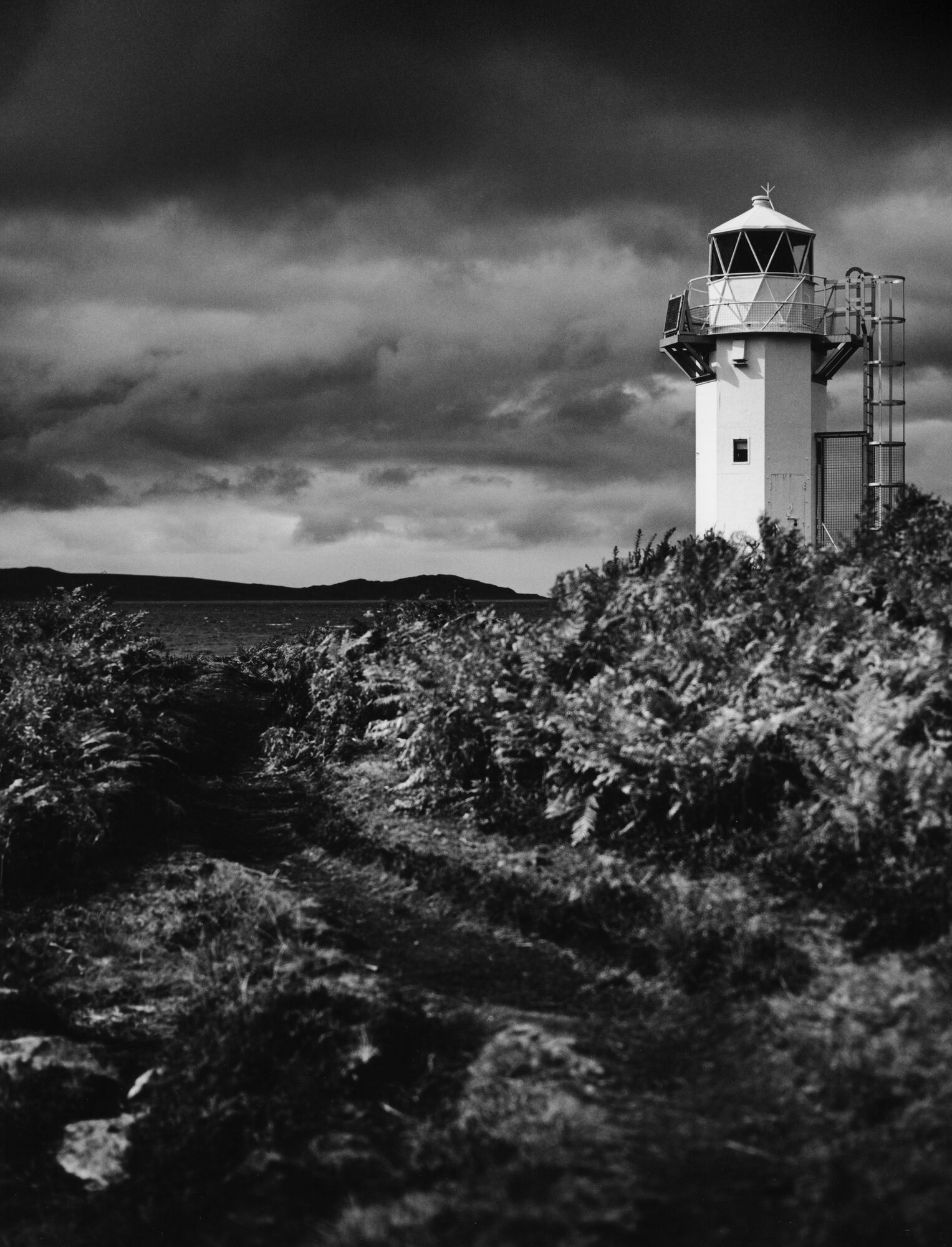 Ullapool lighthouse above the bracken, under a dark sky