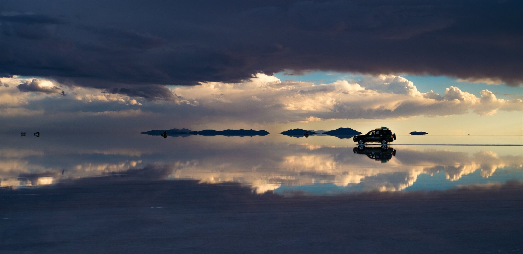 A band of light on the horizon over the mirrored salt flats