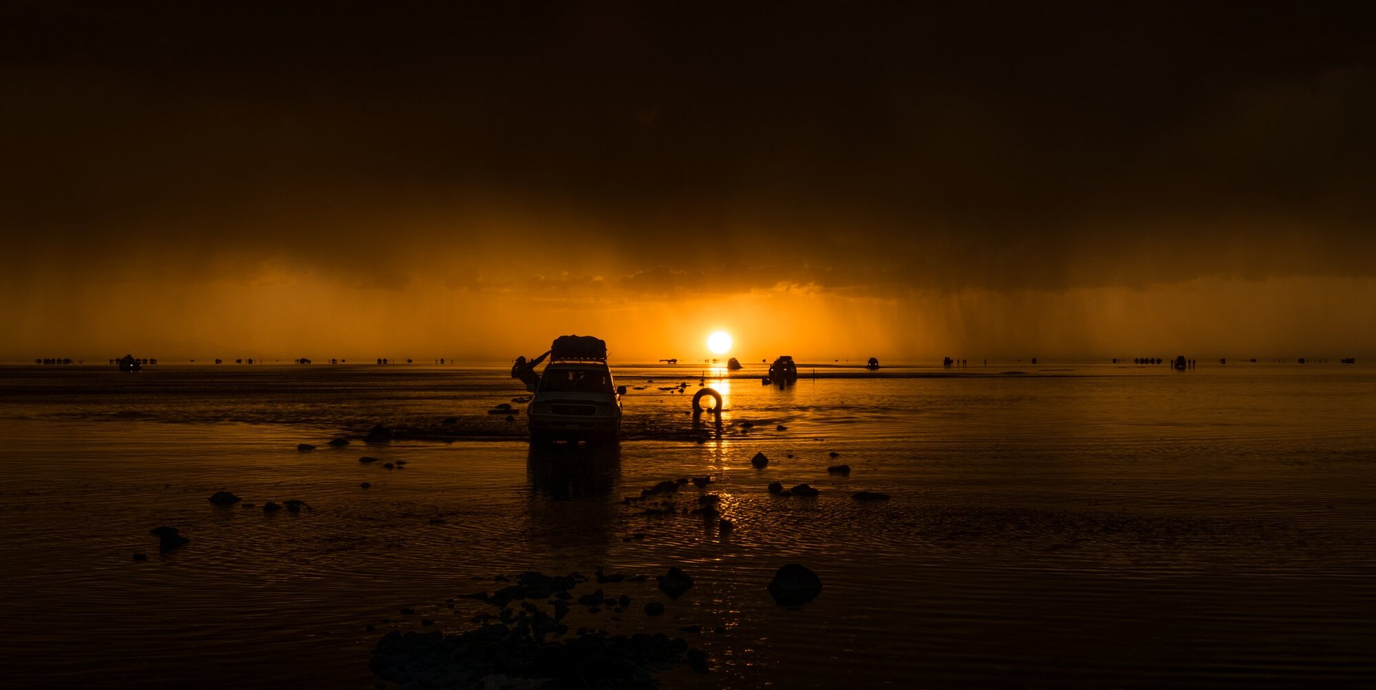 The sun setting behind a jeep on the salt flats