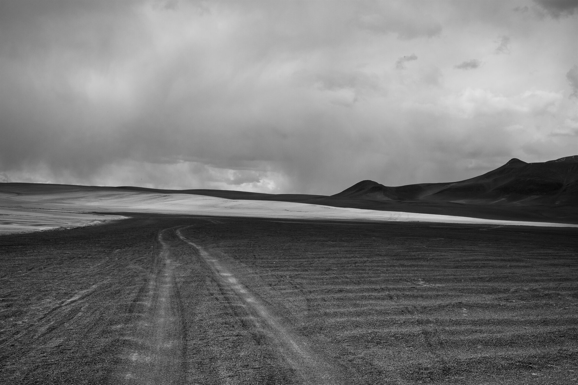 Tyre tracks running across the plain towards the mountains