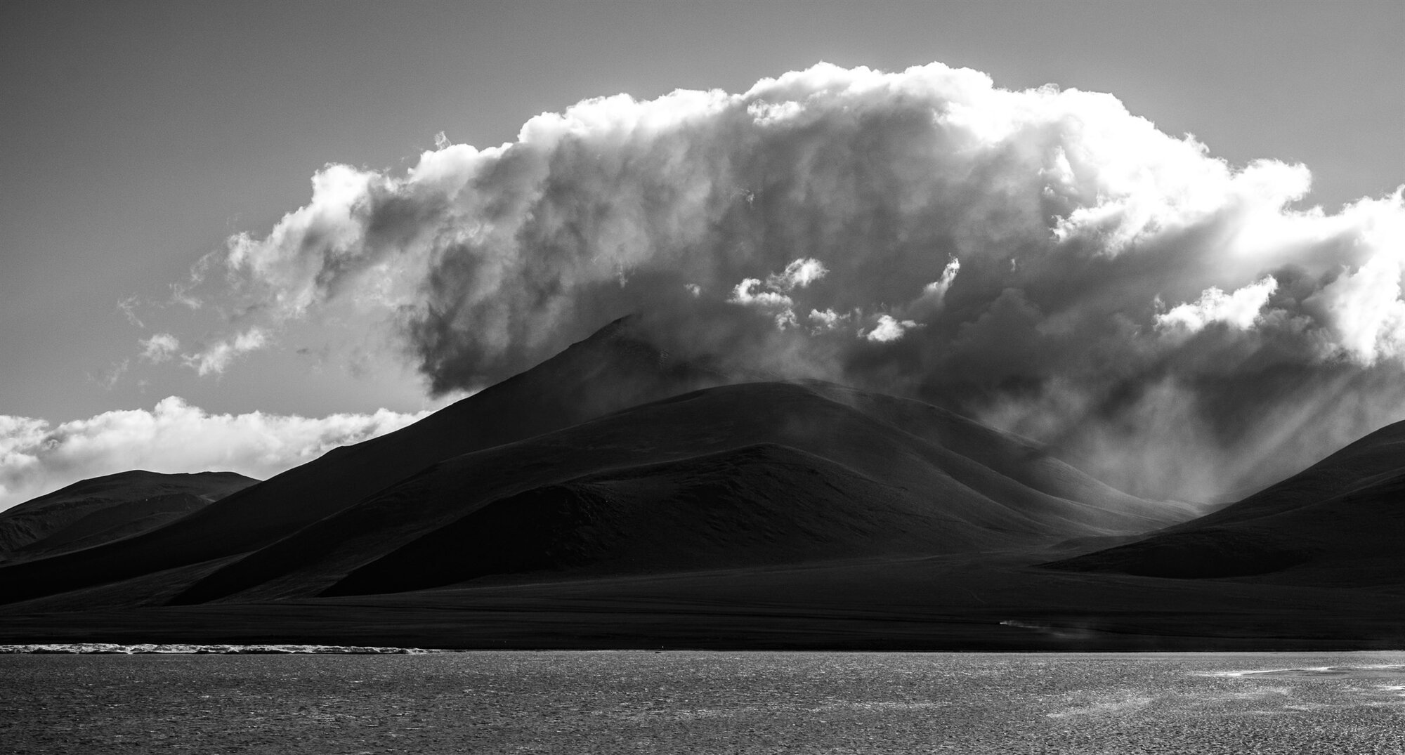 Cloud piling up over a dark volcano