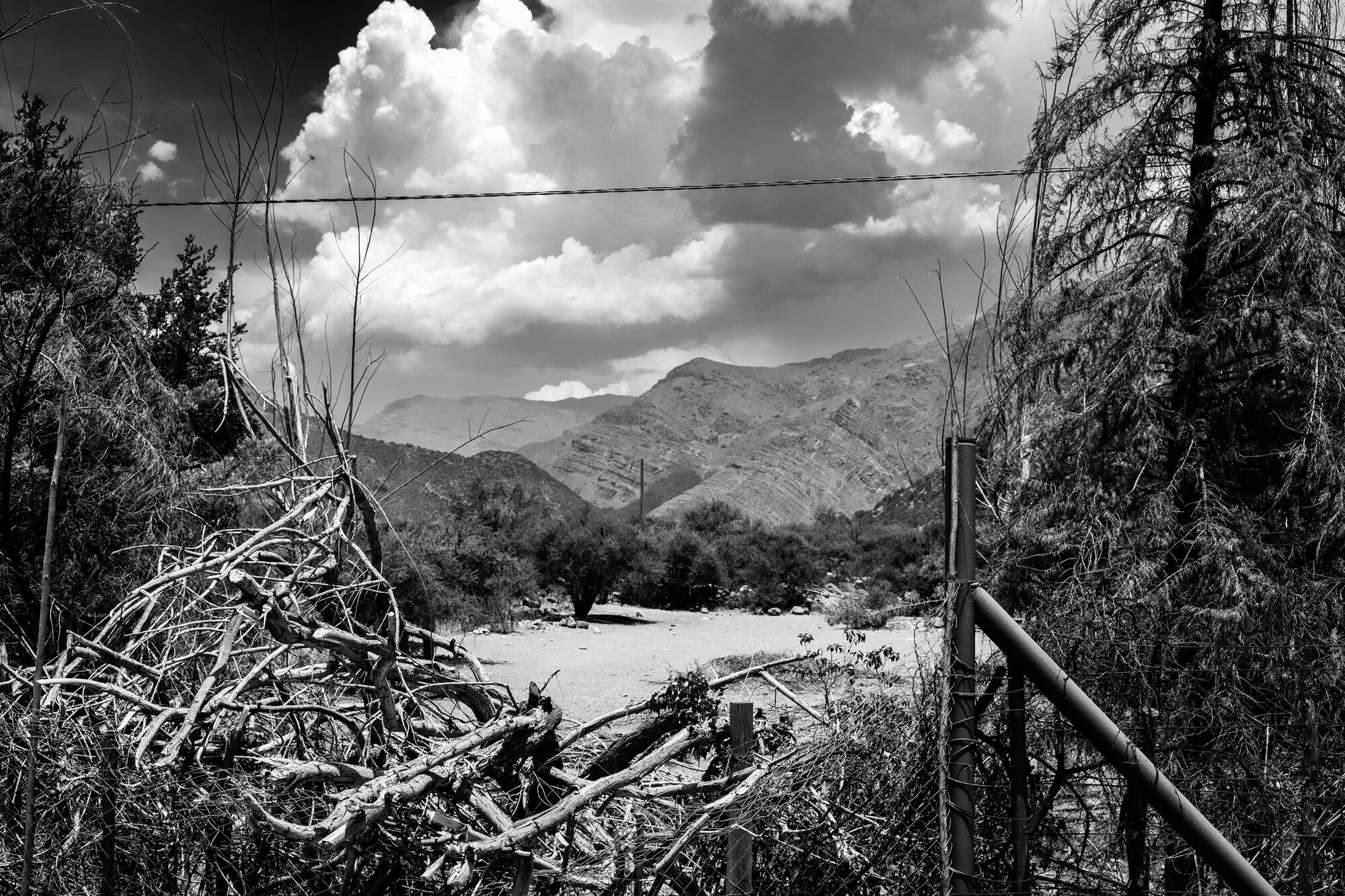 A fence and fallen branches before a mountain valley