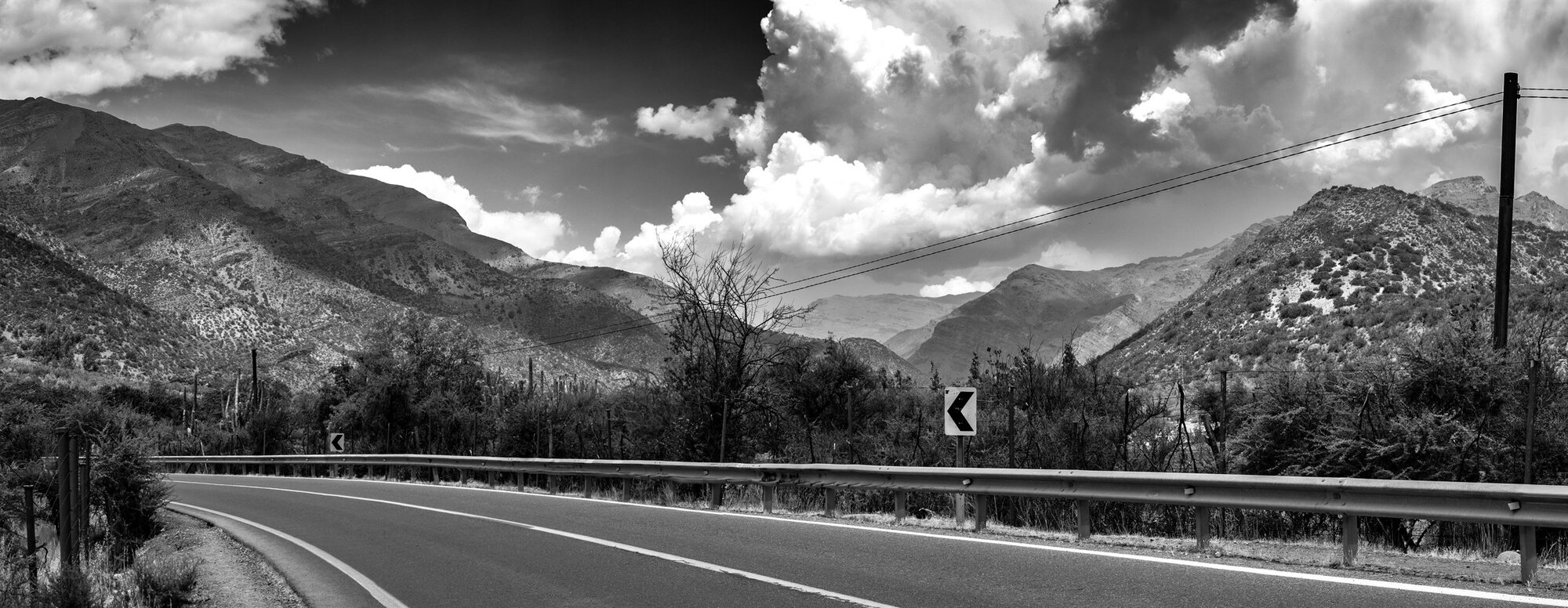 A road curving through the mountains under a dramatic sky