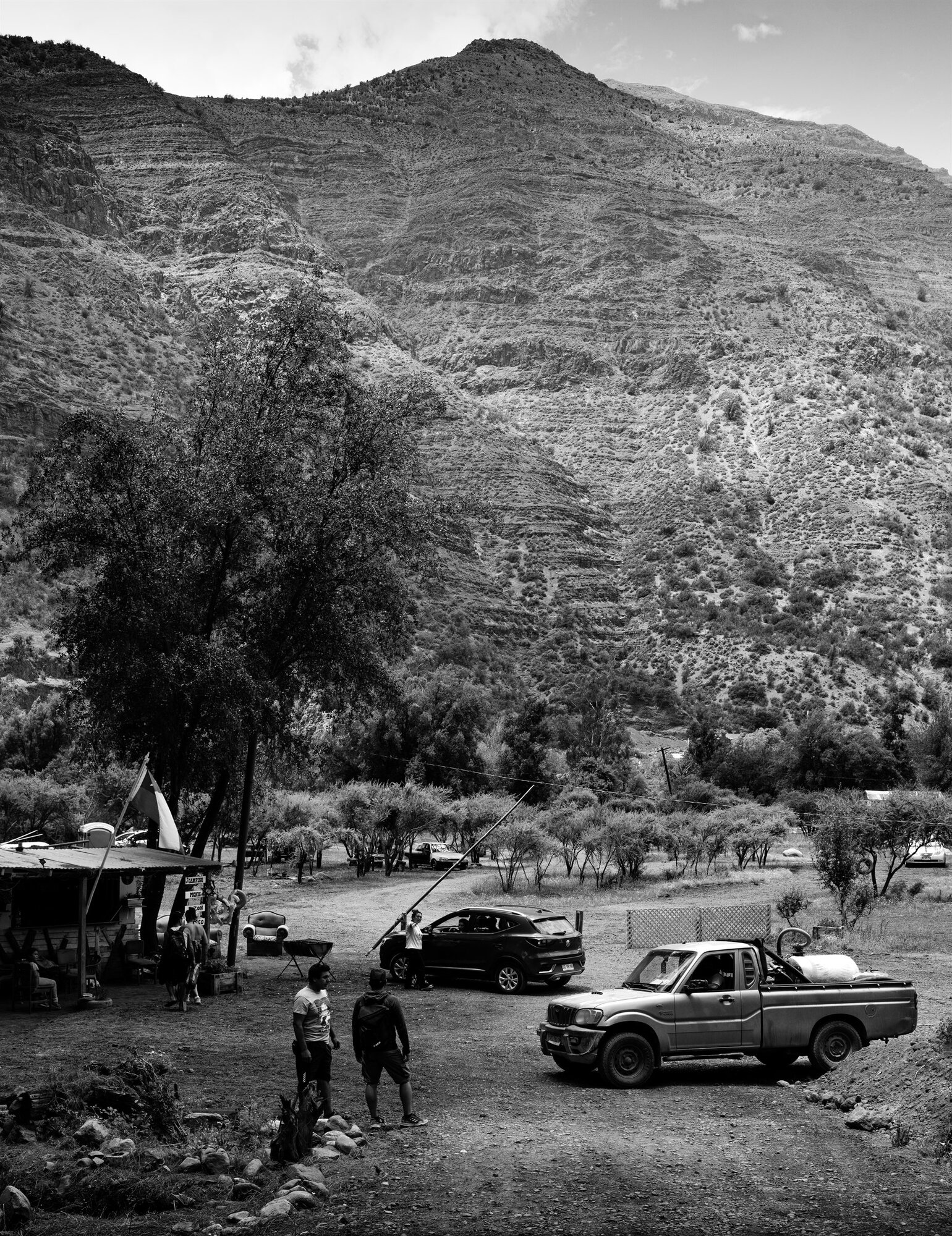 Cars and people below a steep valley side