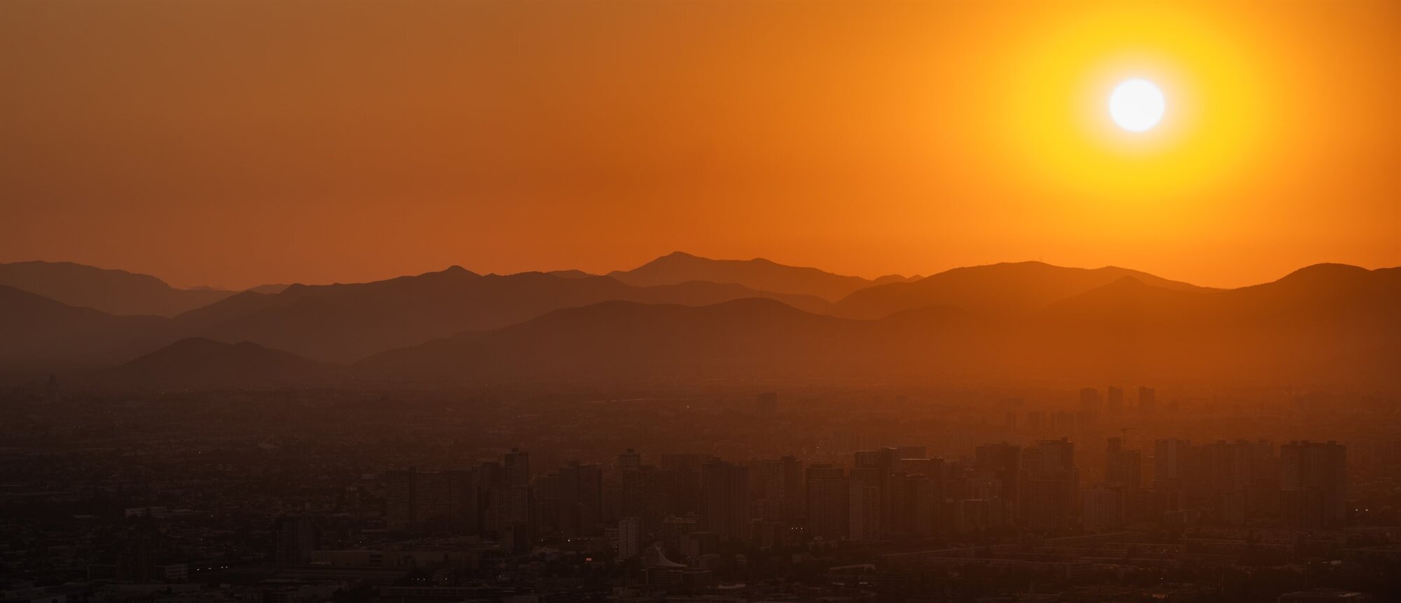 The sun setting in orange over the mountains